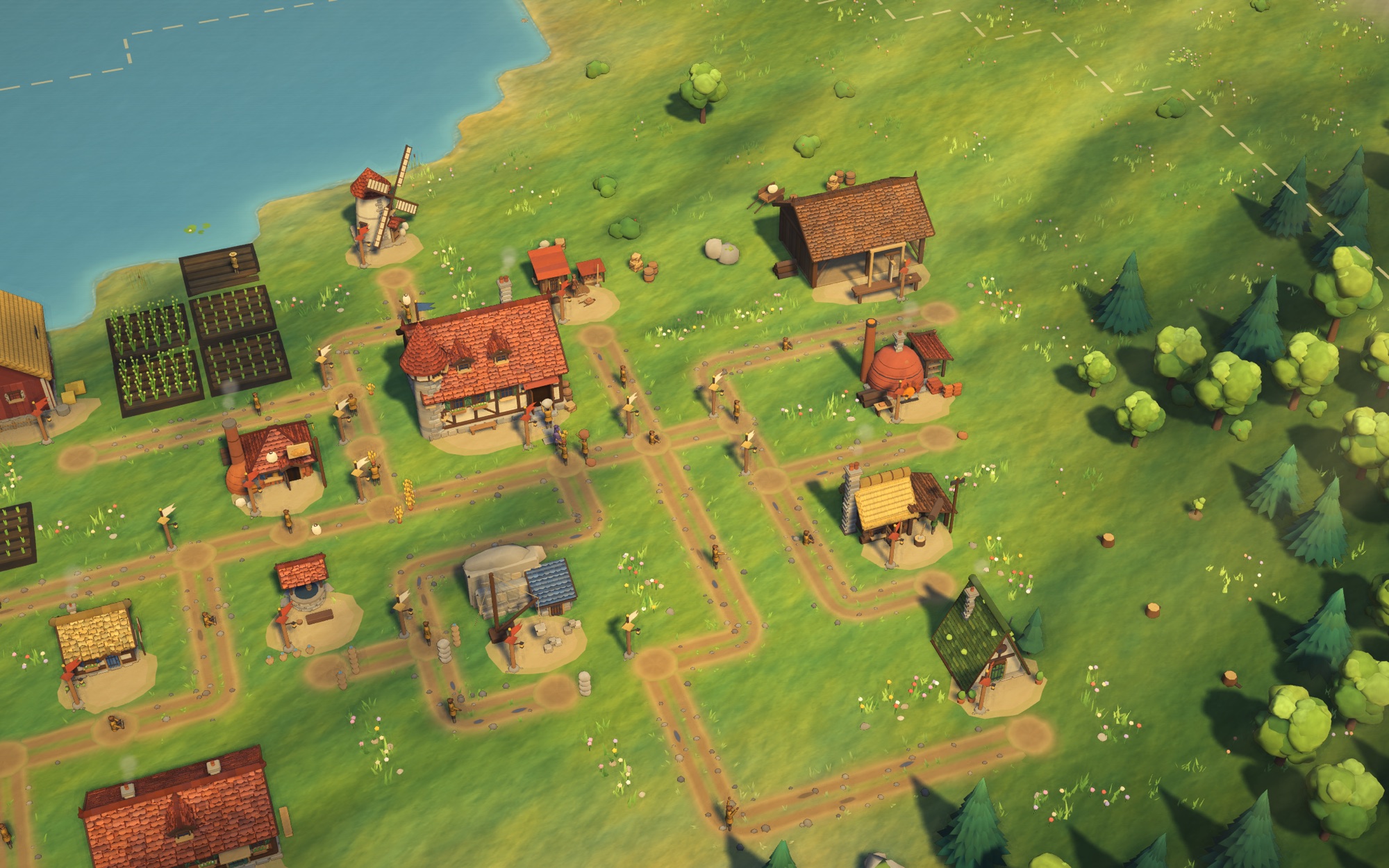 Wide view of a late-game village — winding roads, workshops, fields by the lake and forest at the edge